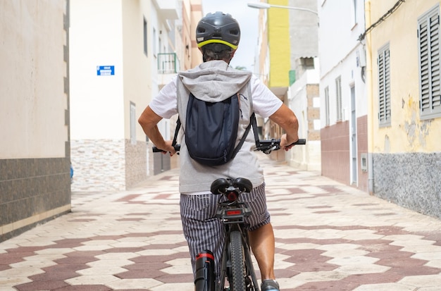 Caucasian cyclist elderly woman in urban street running with her electro bicycle. Healthy lifestyle