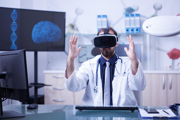 Caucasian doctor wearing a virtual reality headset looking in front of him. Male doctor using modern technology for diagnosis the patients.