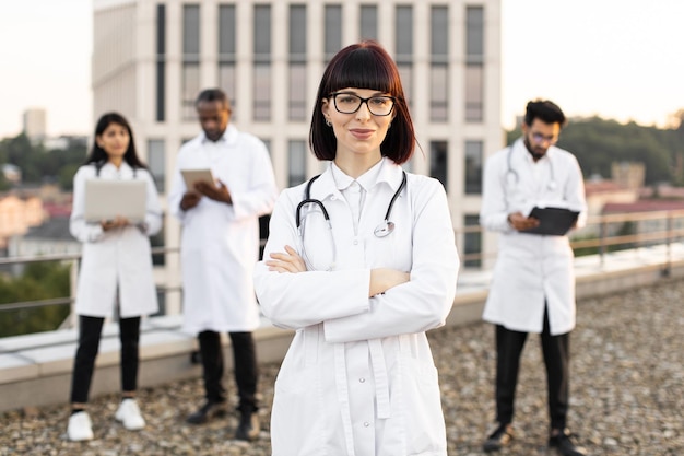 Caucasian doctor in white lab coat posing on camera with crossed hands