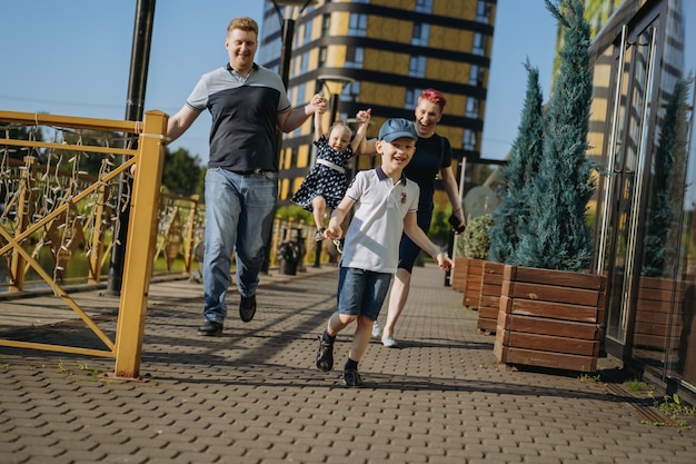 Caucasian family couple walking with baby girl lifting baby by hands woman is happily laughing boy r...