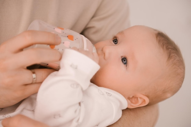 Caucasian father feeds newborn baby girl from a bottle Parent holding rocking child daughter son in hands Authentic lifestyle parenting fatherhood moment