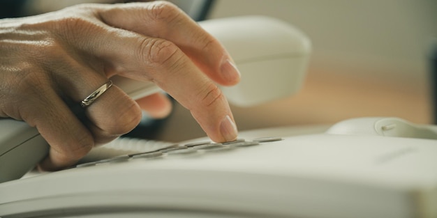 Caucasian female hand holding telephone receiver and dialing phone number