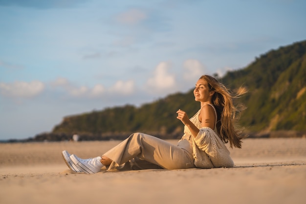 Caucasian female in a wool crop top on a beautiful sunset sitting on the beach