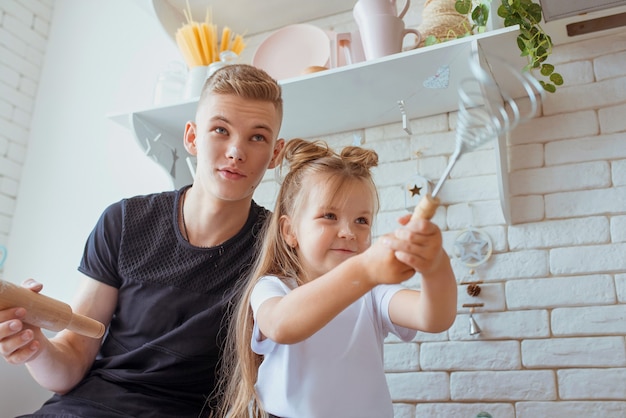 caucasian funny cute siblings in kitchen  little girl with older brother baking in kitchen