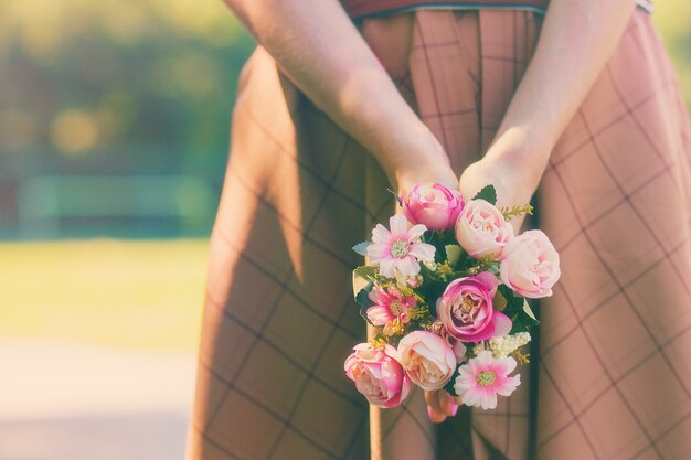 Caucasian girl holding a bouquet of flowers in her hands on the background of a green summer sunny