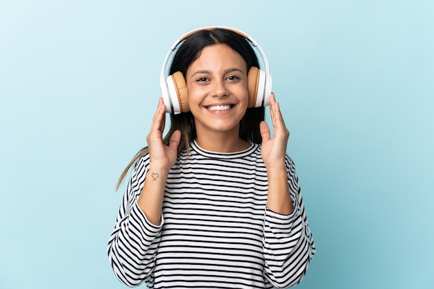 Caucasian girl isolated on blue listening music