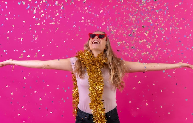 Caucasian girl partying at the disco laughing throwing confetti isolated on a pink background