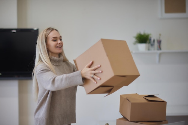 Caucasian girl taping boxes for moving in new apartment