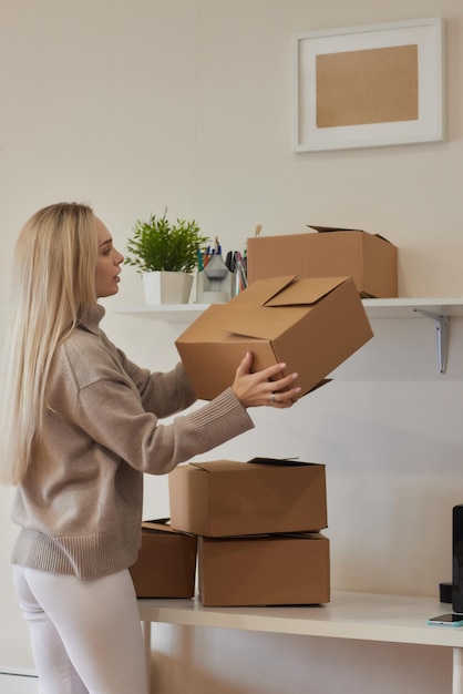 Caucasian girl taping boxes for moving in new apartment