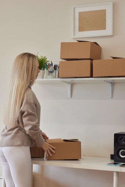 Caucasian girl taping boxes for moving in new apartment