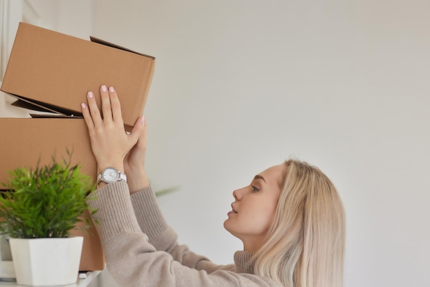 Caucasian girl taping boxes for moving in new apartment