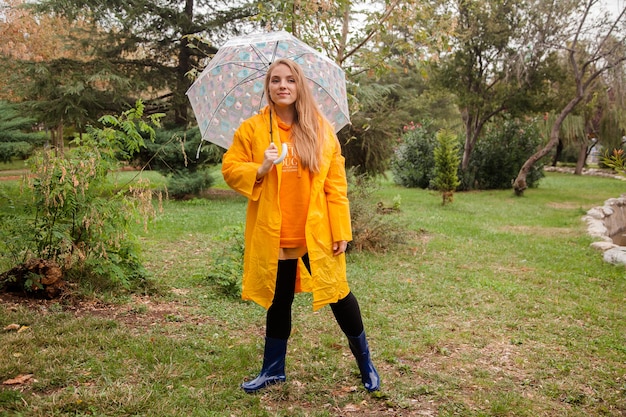 Caucasian girl in a yellow raincoat walking outside in the rainy day in autumn People in fall