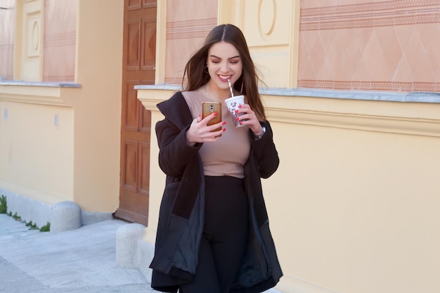 Caucasian girl young woman walking down the street holding coffee to go cup