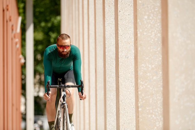 Caucasian handsome young man in protective helmet goes out for bicycle ride through city streets on blurred background Cyclist male ride bike outdoors in urban