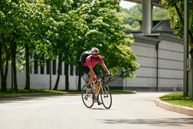 Caucasian handsome young man in protective helmet goes out for bicycle ride through city streets on blurred background Cyclist male ride bike outdoors in urban