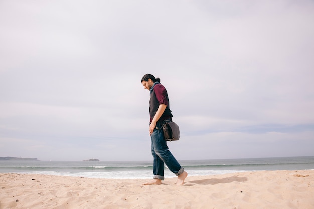 Caucasian hipster man walking alone on the beach with casual clothes