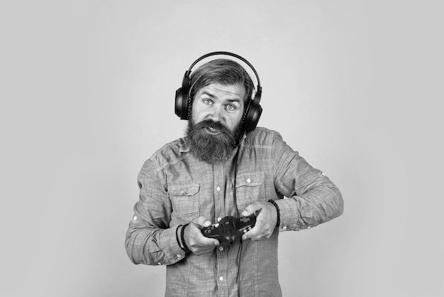 Caucasian hipster with beard and stylish hair in headset with gaming console modern life