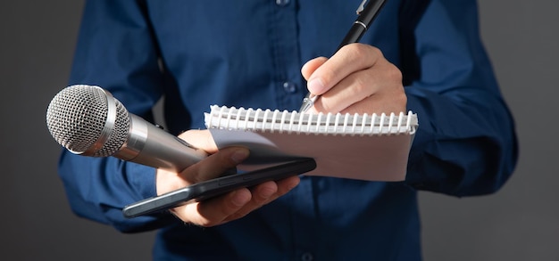 Caucasian journalist holding microphone notepad and pen