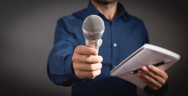 Caucasian journalist holding microphone notepad and pen