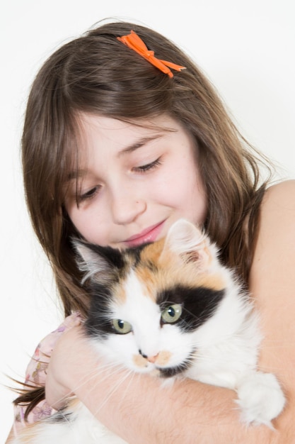 Caucasian little girl holds her cat in the arms and look