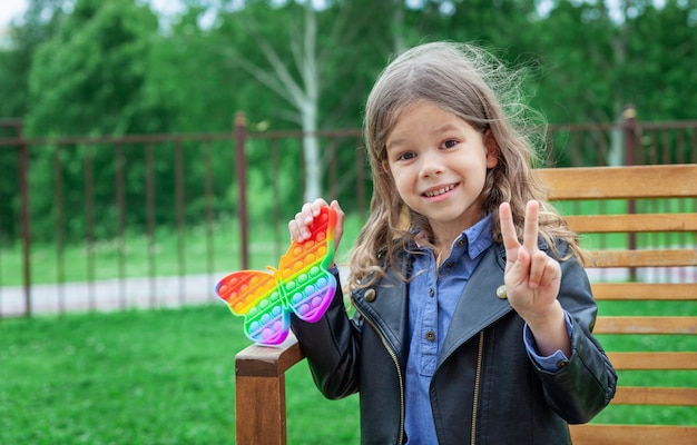 Caucasian little girl playing with pop it silicone trendy rainbow colow toy