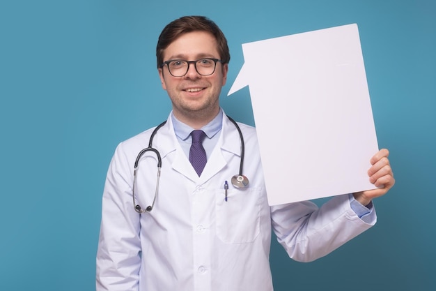 Photo caucasian male doctor holding placard over blue background