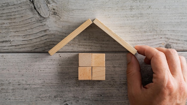 Caucasian male hand building a house of wooden blocks