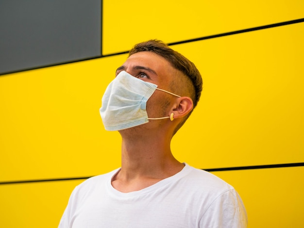 Caucasian male with a mask standing on yellow wall background