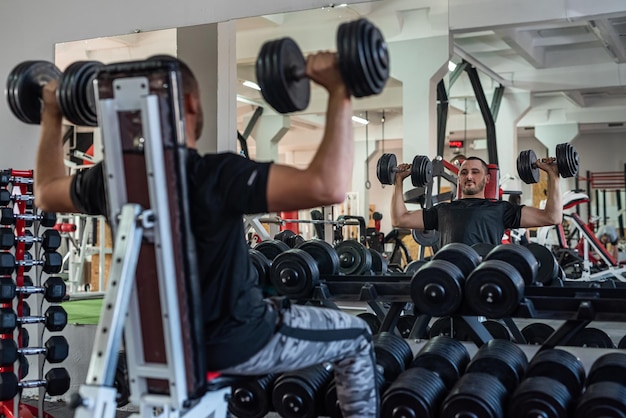 Caucasian man doing workout with dumbbells in gym