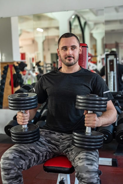 Caucasian man doing workout with dumbbells in gym