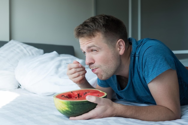 Caucasian man eating watermelon at home