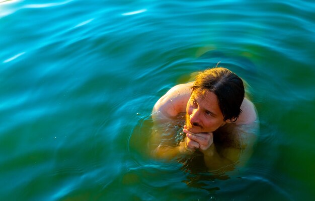 Caucasian man floating in a swimming lake with blue water