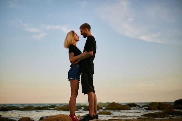 caucasian man and girl stand embracing on the seashore on the beach at sunset