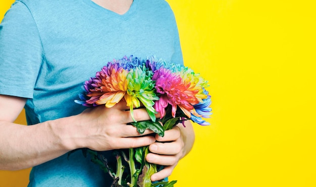 A caucasian man holding a bouquet of colored chrysanthemums