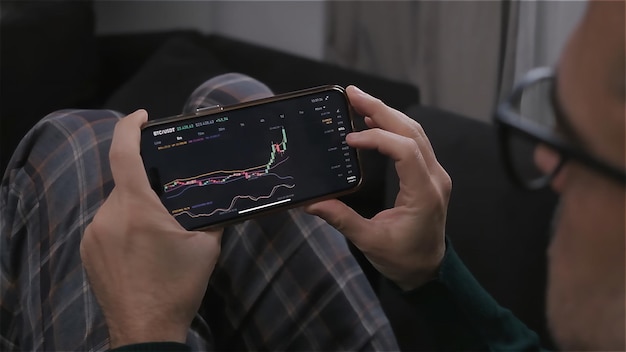 Caucasian man at home trade and earn money on the cryptocurrency exchange online using his phone