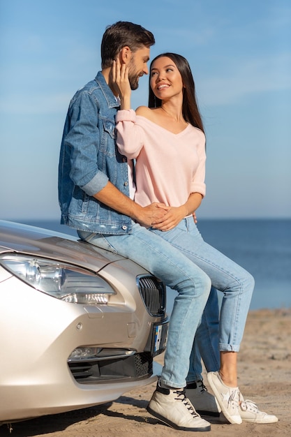 Caucasian man hugging asian woman while sitting on the convertible