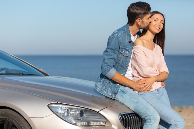 Caucasian man kissing asian woman while sitting on the auto