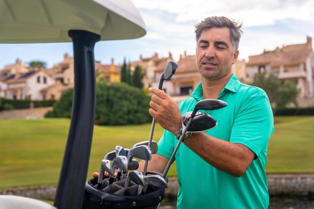 Caucasian man playing golf at golf club checking golf clubs in buggy