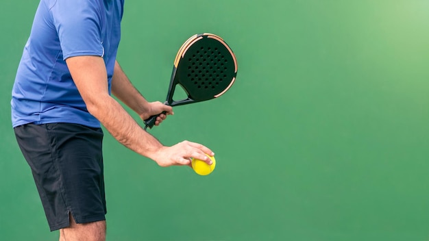 Caucasian man playing a match open with black padel racket and yellow ball