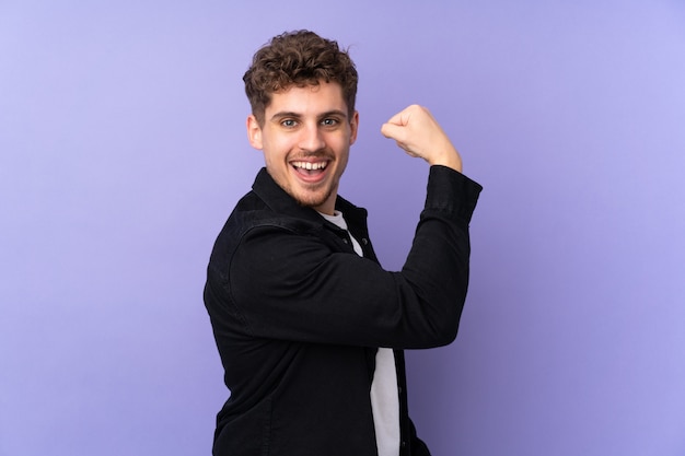 Photo caucasian man on purple wall doing strong gesture