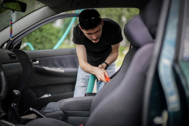 Caucasian man vacuuming a car at a gas station