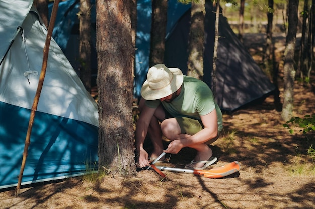 Caucasian man wearing a hat putting up a tent Family camping concept