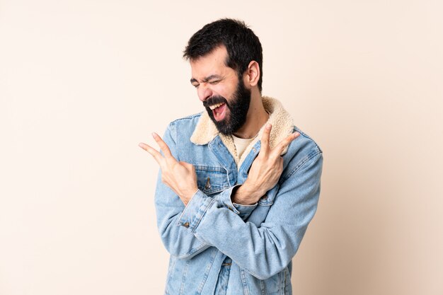 Caucasian man with beard over wall smiling and showing victory sign