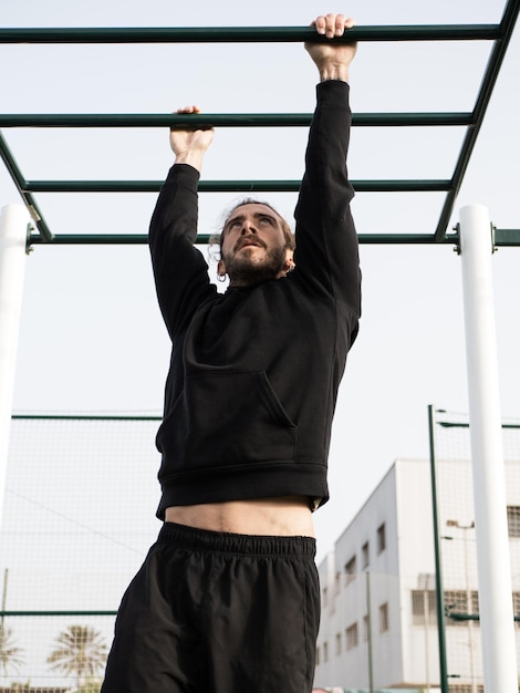 Caucasian man working out with monkey bars oudoor in the calisthenics park