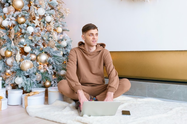 Caucasian man working on winter holidays in living room sitting on floor near