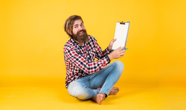 Caucasian mature hipster with trendy hairstyle in checkered shirt making notes in folder paper documents notice