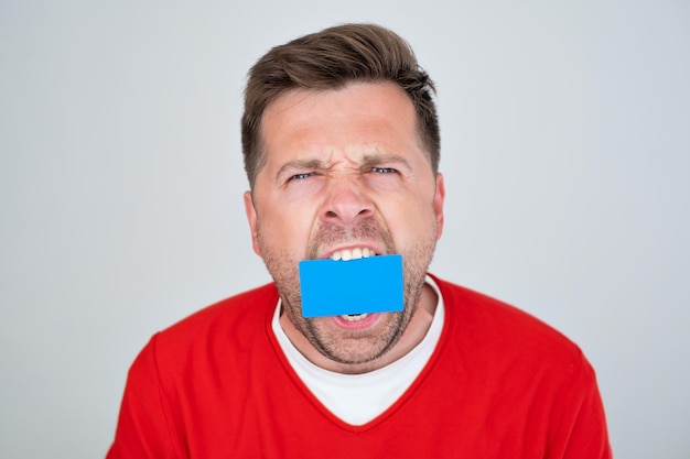 Caucasian mature man holding credit card at his mouth