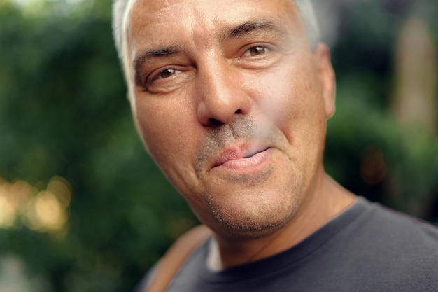 Caucasian mature middle aged man smoking cigarette outdoors. Nicotine addiction. Copy space