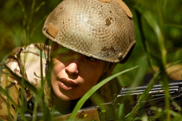 Caucasian Military lady woman in tactical gear posing for photo at summer season Wearing green camo uniform and assault rifle in military gear and headset lady is looking at side