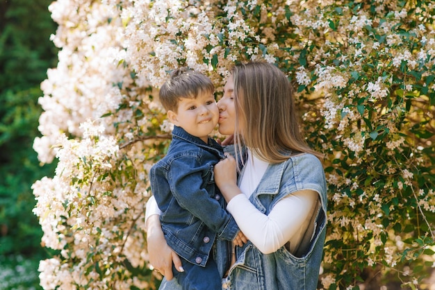 Caucasian mom kisses her threeyearold son on the cheek on a spring walk in the park